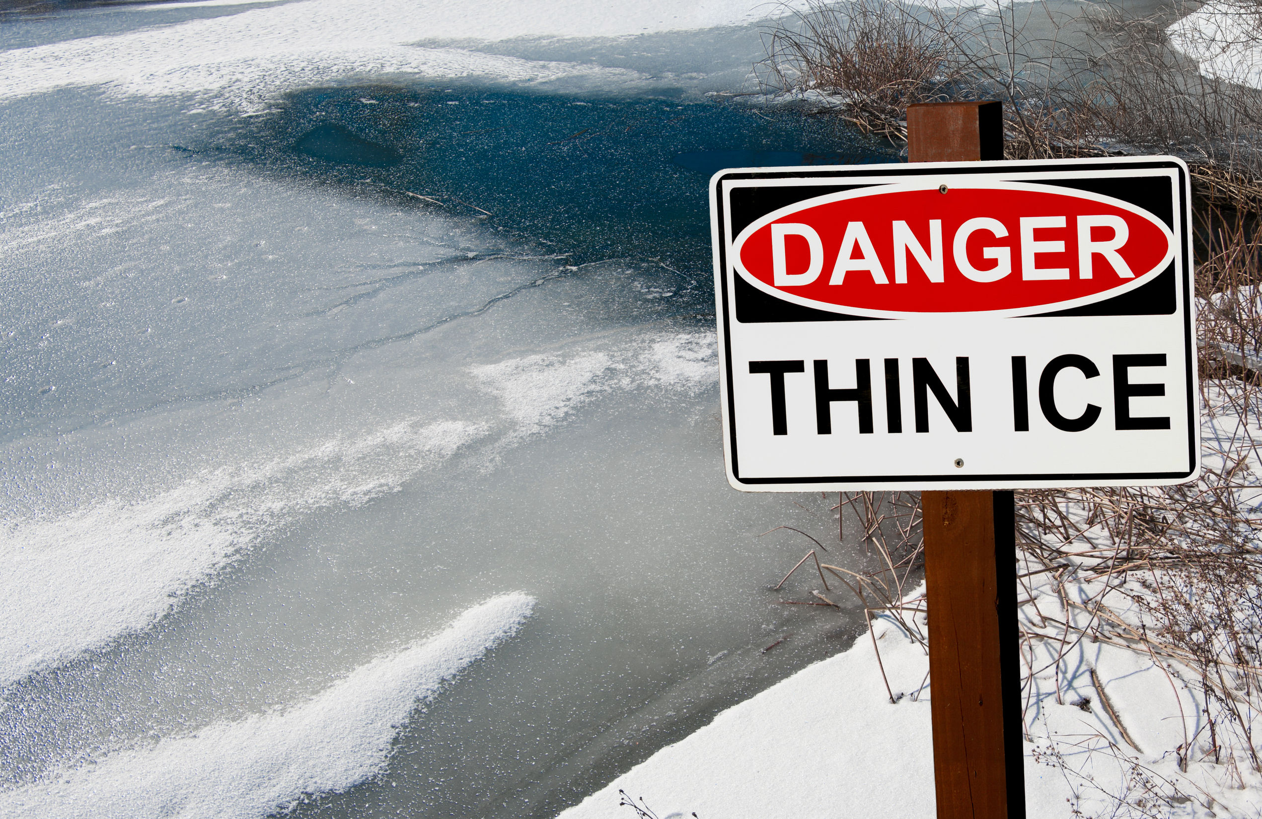 thin ice warning sign: a sign warns of danger as ice thaws on a pond in southern wisconsin.